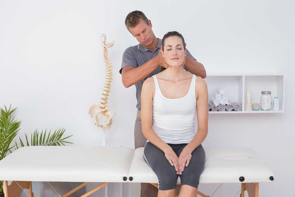 A chiropractor gently adjusting an adult client's upper back in a bright, comfortable treatment room.